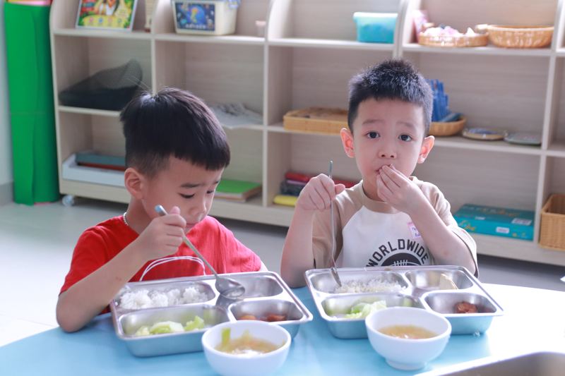 Hai bé tự xúc cơm trong bữa trưa bán trú